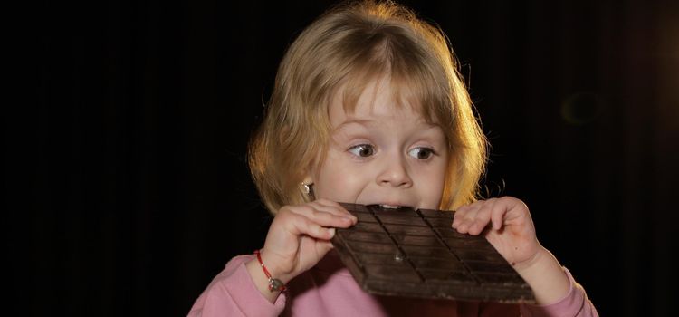 A csokoládét majszoló kisgyerek képe azt sugallja, hogy a keserű csoki jótékony hatása mellett a mértékletes fogyasztásra is érdemes figyelni. Kislány hatalmas étcsokoládé táblába harap, miközben az étcsoki hatása a mennyiségtől is függ, ezért nem érdemes túlzásba esni.